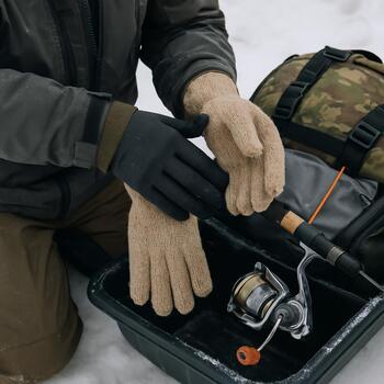 Angler changing gloves and layers beside a packed sled