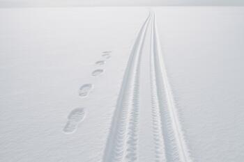 Flat snow surface with clear boot and sled tracks on the lake
