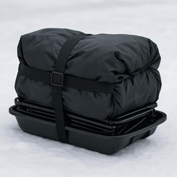 Packed portable ice fishing shelter and sled with gear on top of frozen lake